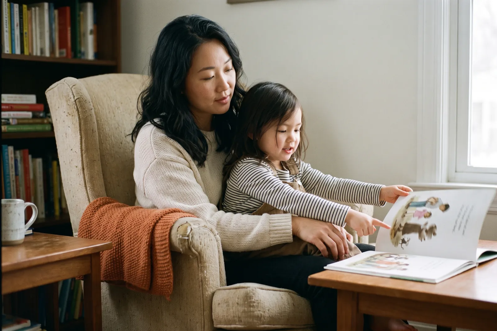 A four-year-old girl on her mother's lap points at an illustration in a picture book
